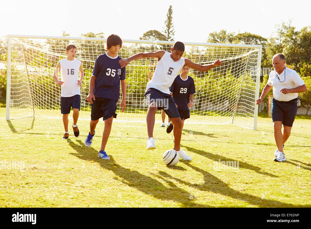Los miembros de la Escuela Secundaria Masculina jugando fútbol coinciden Foto de stock