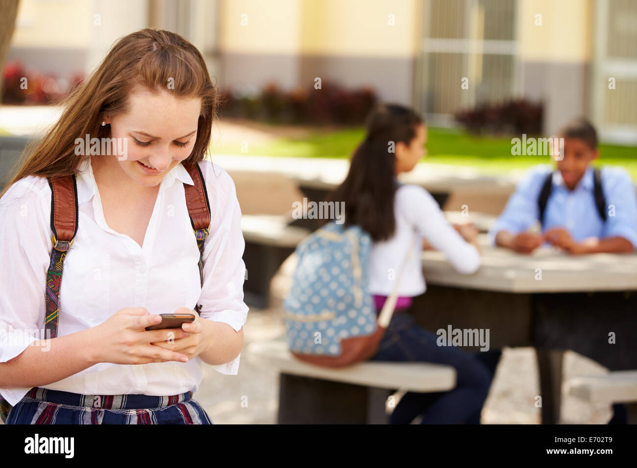 Estudiante de la escuela secundaria femenina mediante teléfono en el Campus de la escuela Foto de stock