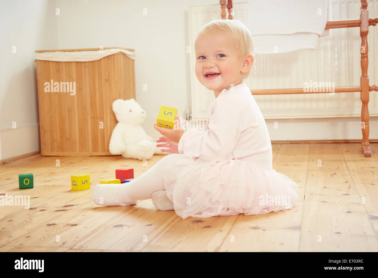Retrato de la sonrisa de bebé niña jugando en el piso con bloques de construcción Foto de stock