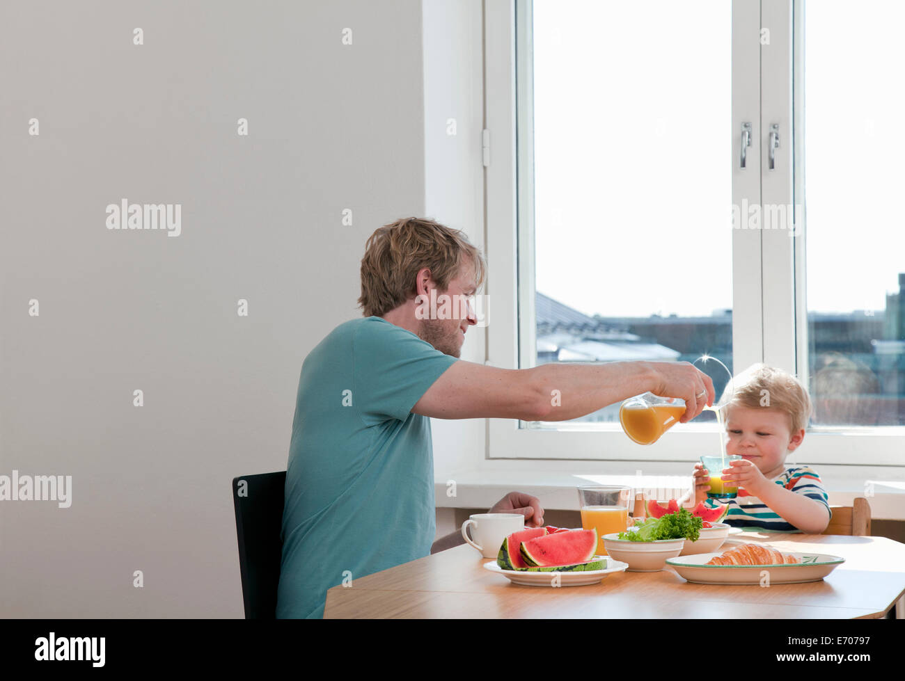 Padre y un hijo pequeño de desayunar en la mesa de la cocina Foto de stock