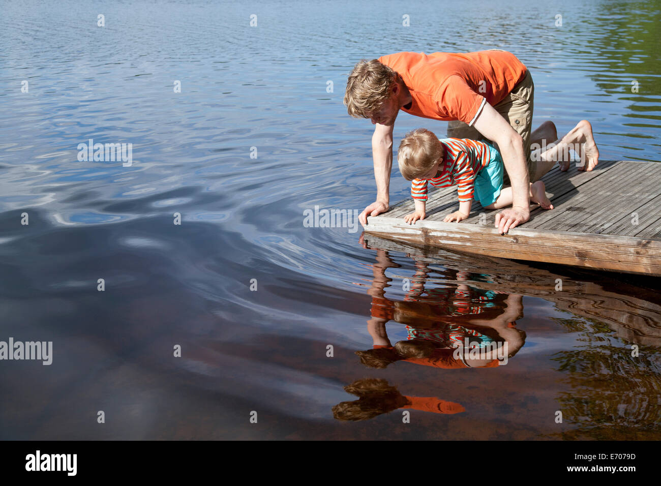 Padre e hijo mirando hacia el lago desde el muelle, Somerniemi, Finlandia Foto de stock