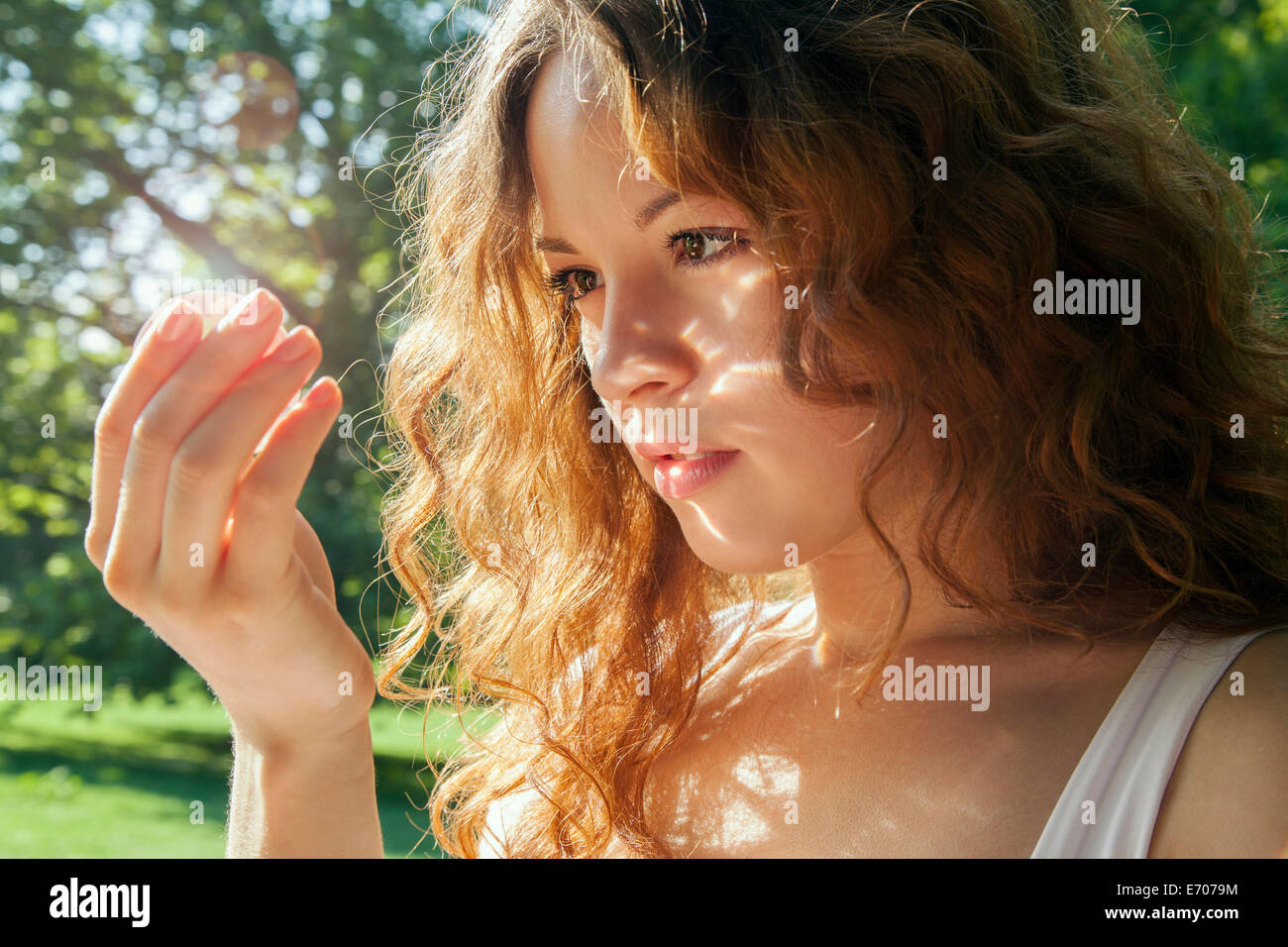 Retrato de mujer joven mirando a algo brillante en la mano Foto de stock