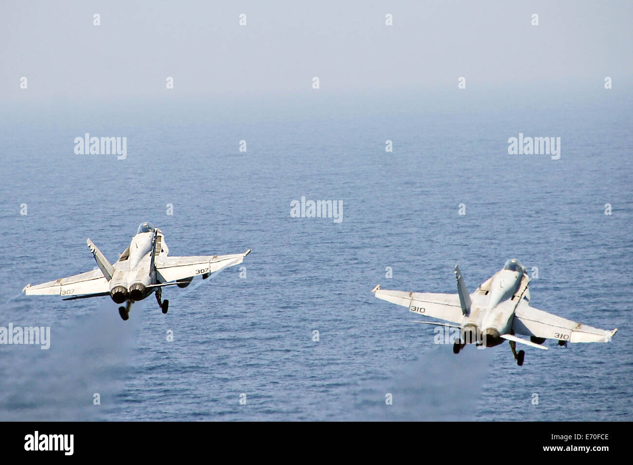 Dos US Navy F/A-18 C Hornet aviones de combate despega desde la cubierta de vuelo del portaaviones USS George H.W. Bush el 30 de agosto de 2014 en el Golfo Pérsico. Los pilotos están volando de ataques aéreos dirigidos contra los extremistas conocidos como el Estado islámico en Irak y el Levante. Foto de stock