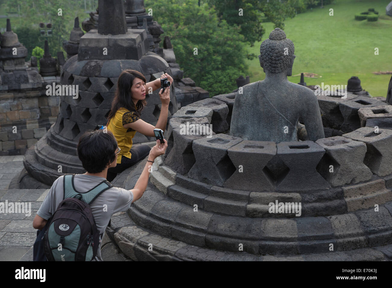 Borobudur, Java, Indonesia. Los turistas fotografiando estatua de Buda. Foto de stock