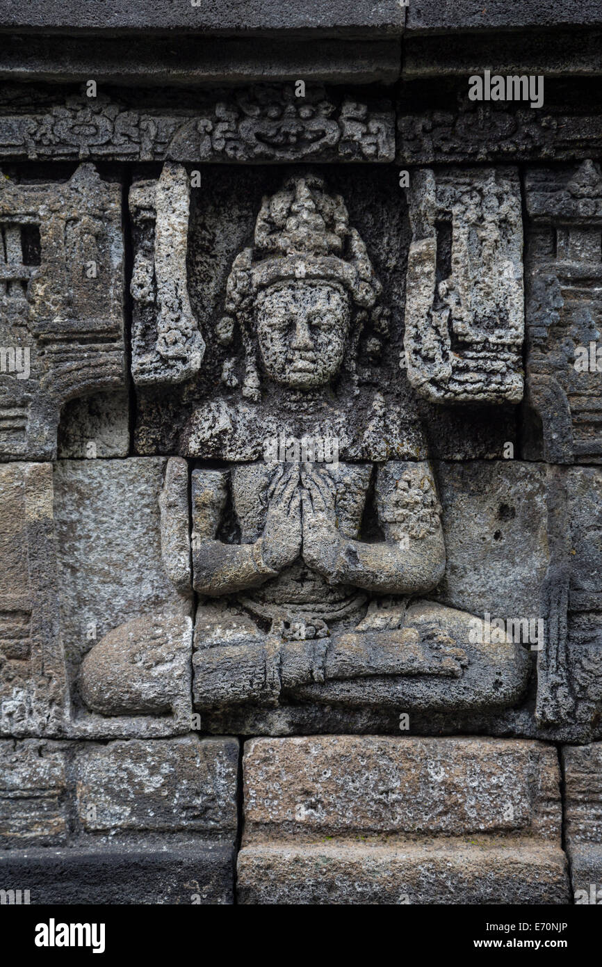 Borobudur, Java, Indonesia. Talla de piedra, sentado en la postura del loto, con las manos juntas. Foto de stock