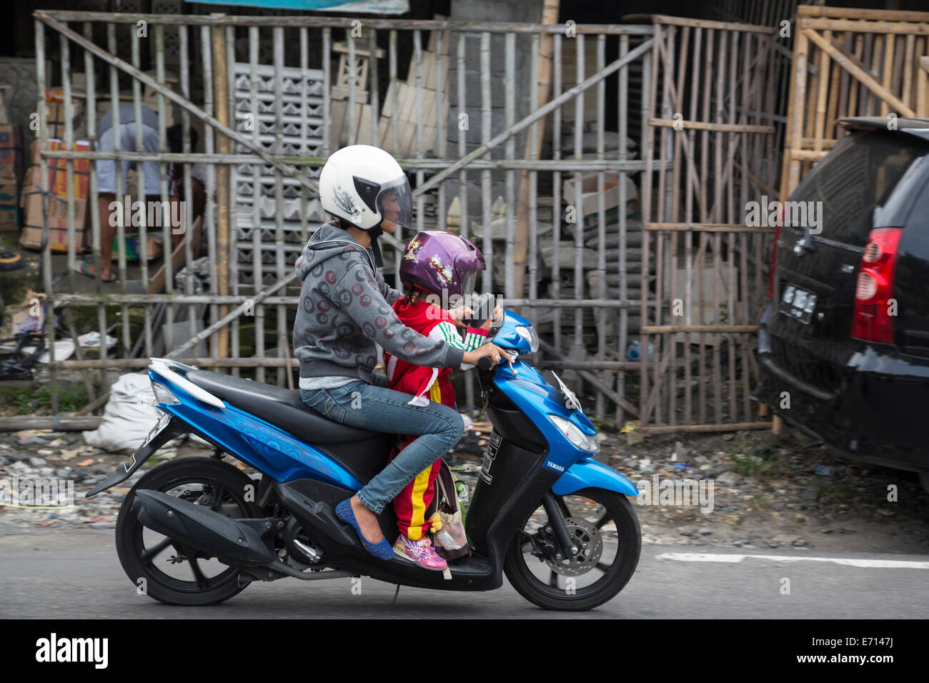 Yogyakarta, Java, Indonesia. La seguridad vial. La madre y la niña en la moto con cascos. Foto de stock