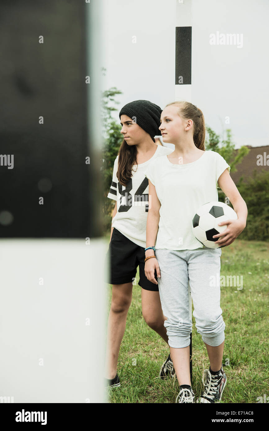 Dos chicas adolescentes con una pelota de fútbol de pie sobre un terreno de  fútbol Fotografía de stock - Alamy