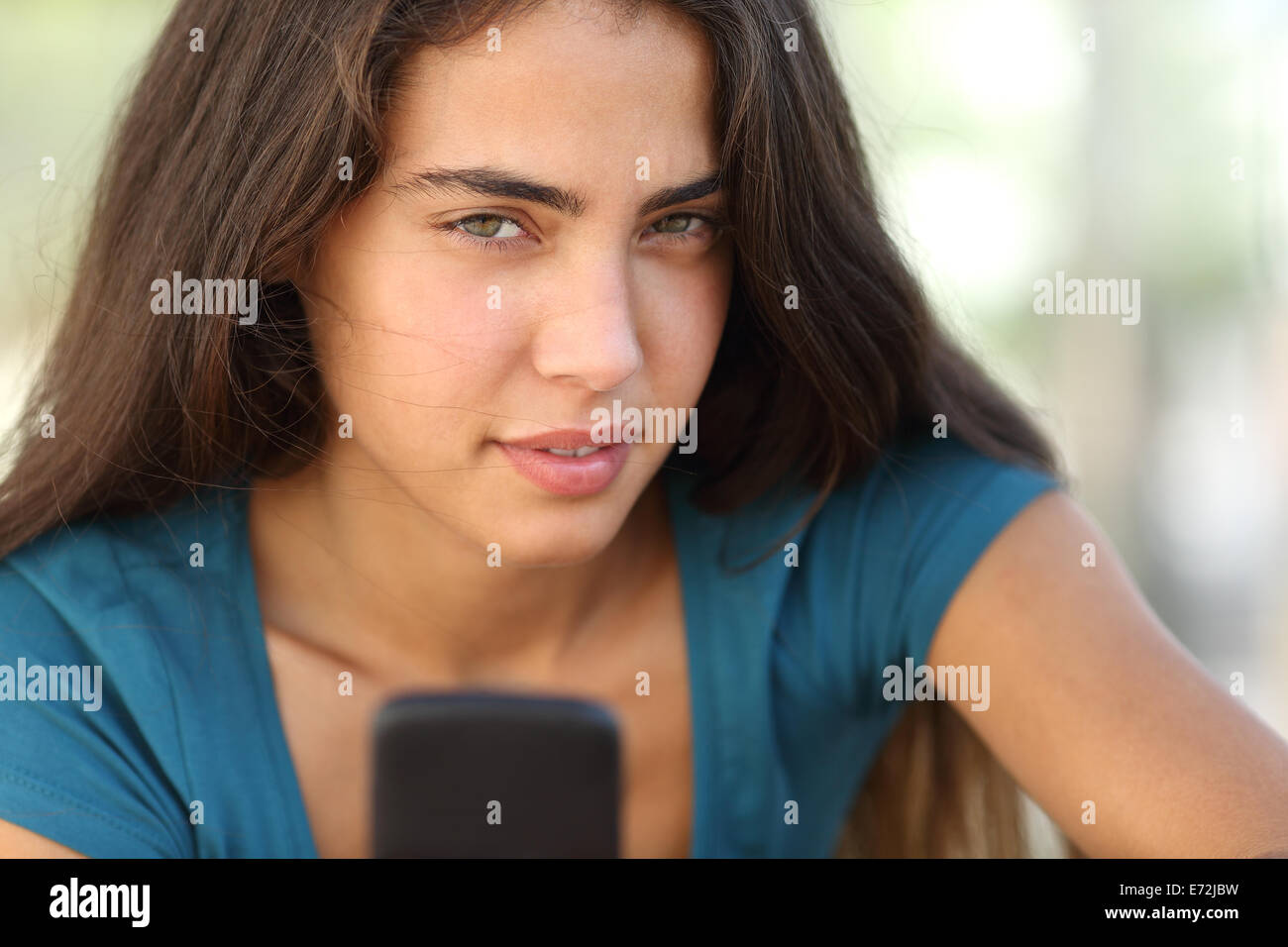 Retrato de una muchacha adolescente con un teléfono inteligente mirando a la cámara Foto de stock