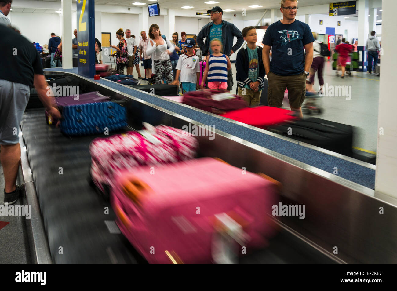 La gente espera en la cinta de equipajes en el aeropuerto de East Midlands para su equipaje Foto de stock