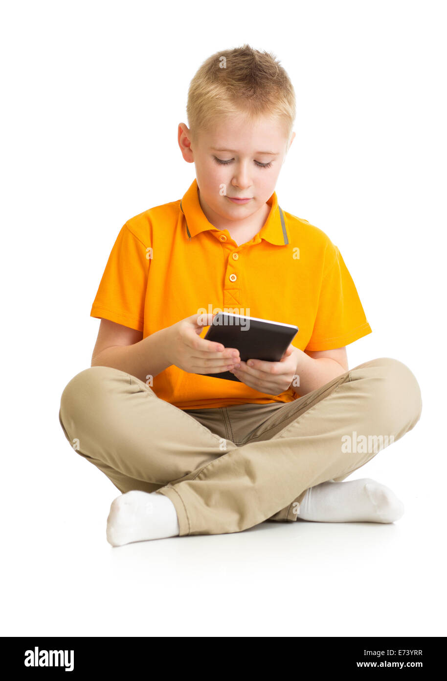 Pensativo kid muchacho sentado con tablet pc o phablet aislado Foto de stock