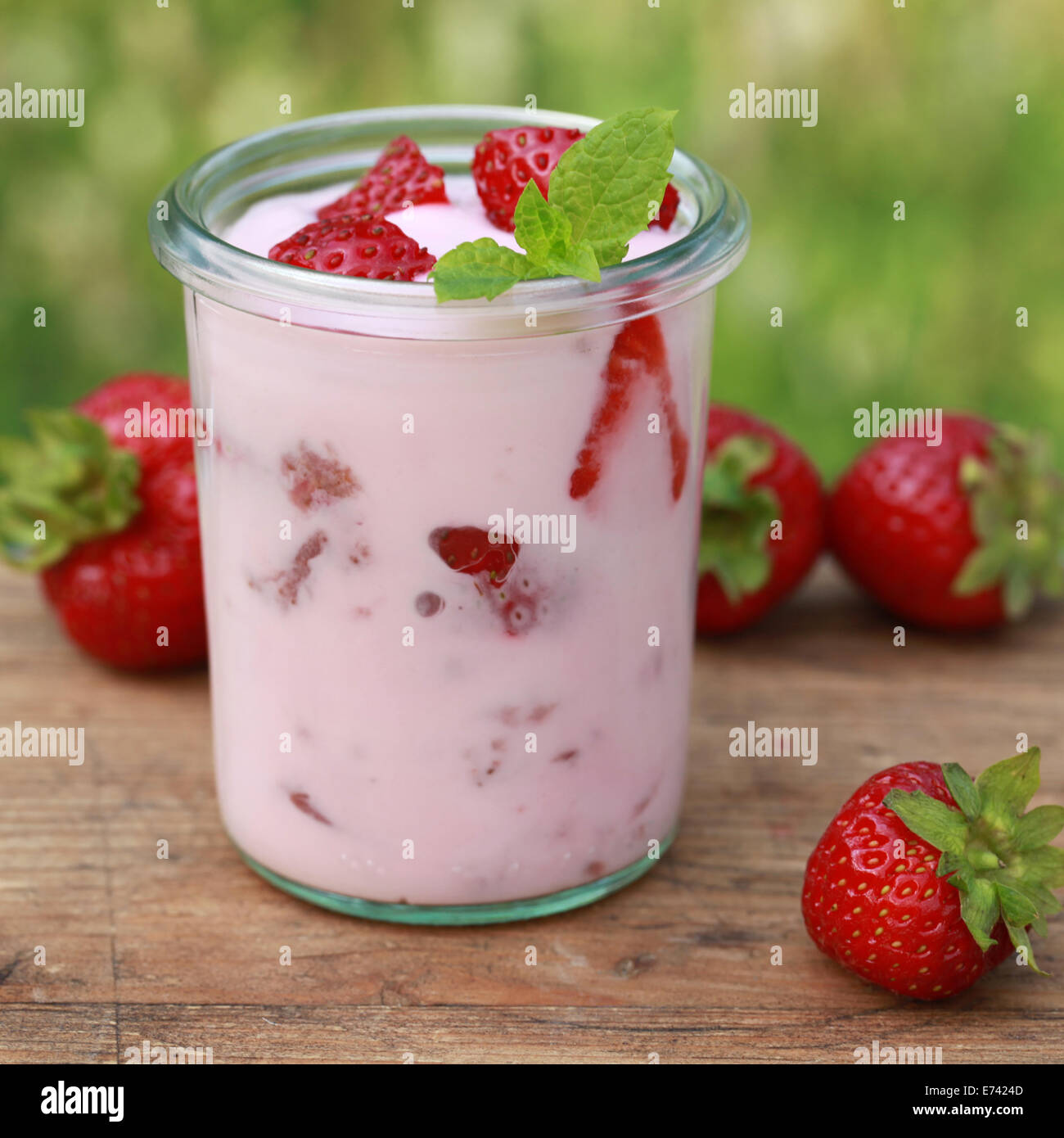 Yogur de fresa en un frasco de vidrio con fresas frescas sobre una mesa de  madera Fotografía de stock - Alamy