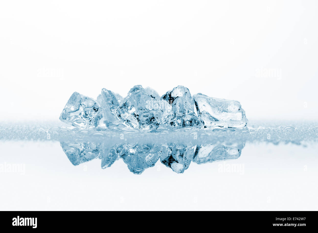 Cubitos de hielo con gotas de agua, sobre fondo blanco con reflejos Foto de stock