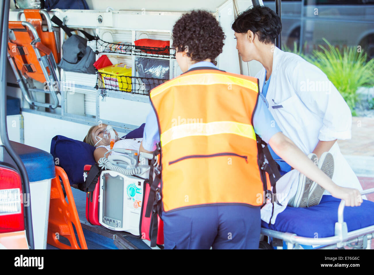Paramédicos wheeling paciente fuera de ambulancia Foto de stock