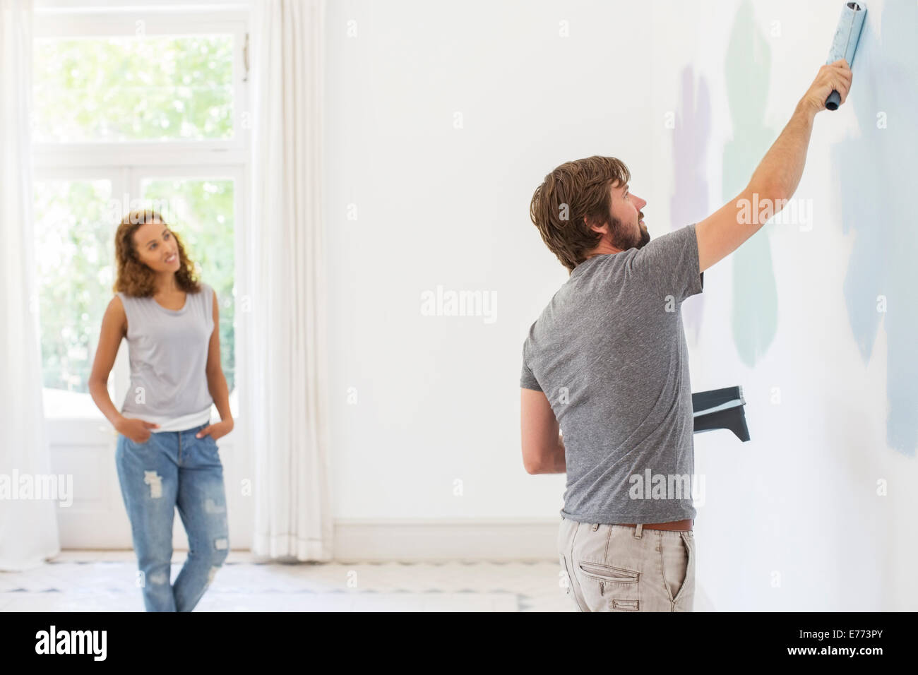 Hombre de pintar una pared con novia observando Foto de stock