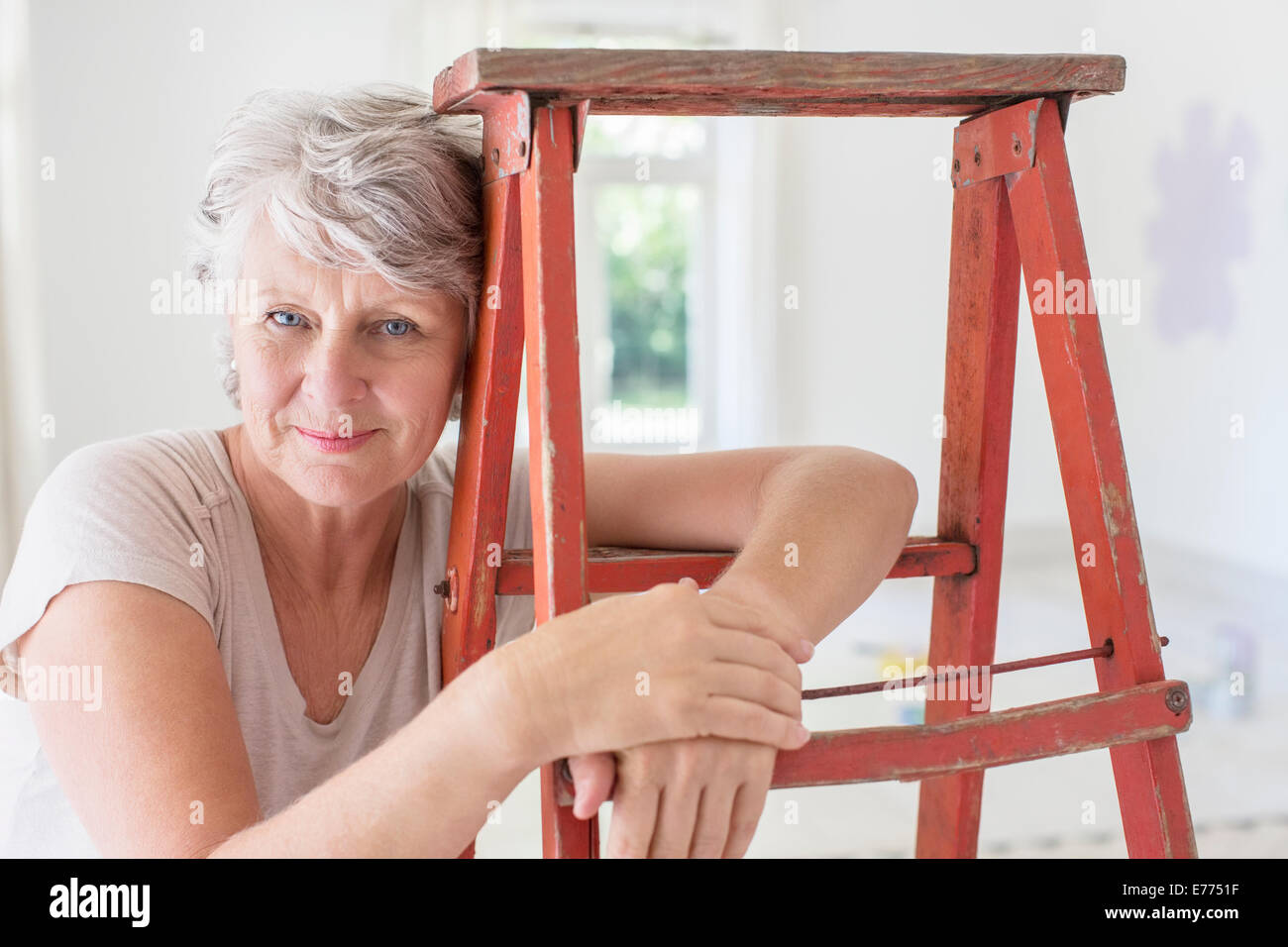 Mujer de edad, apoyándose en la escalera en el salón Foto de stock