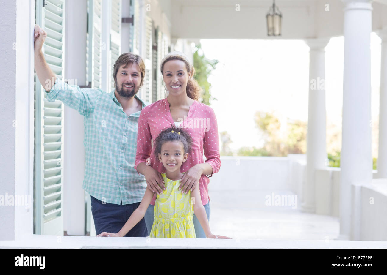 Familia sonriendo en porche junto Foto de stock