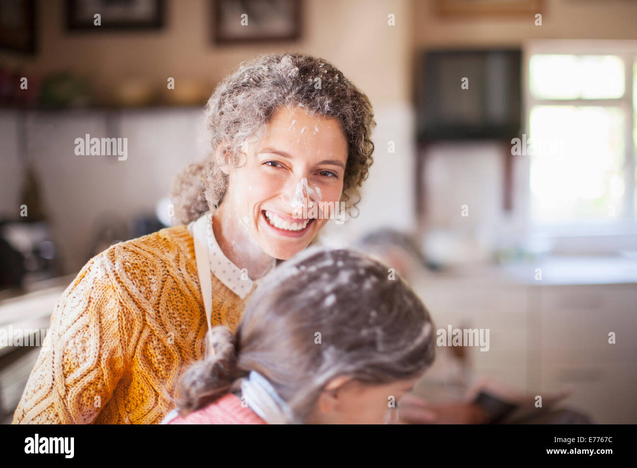 Madre e hija jugando con harina en la cocina. Foto de stock