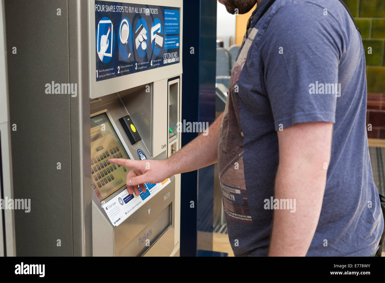 Persona que compra un billete de tren en una máquina de billetes en una estación de ferrocarril, Nottingham, Inglaterra, Reino Unido. Foto de stock