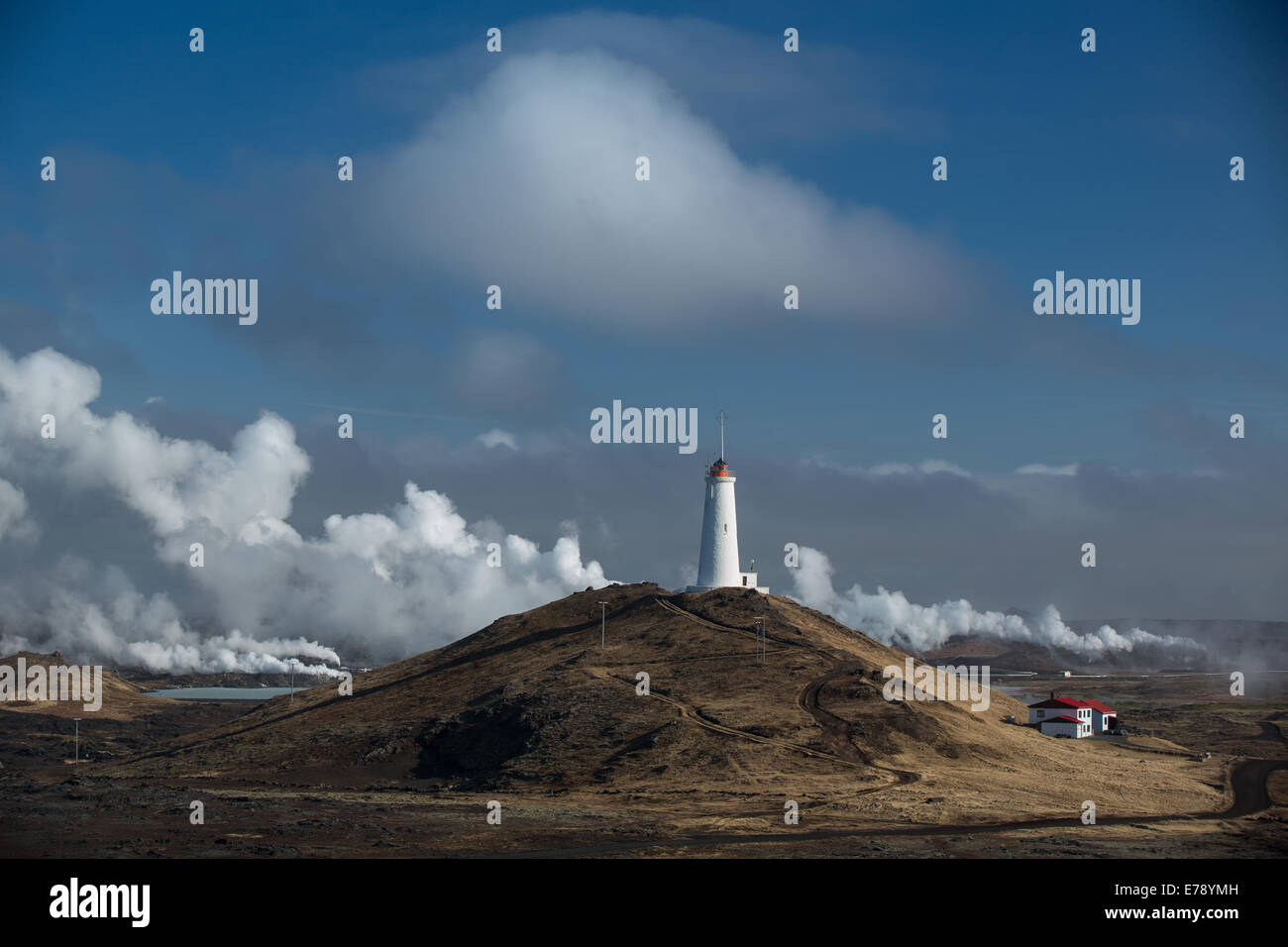 El vapor de la central eléctrica geotérmica y el faro en la península de Reykjanes, Islandia Foto de stock