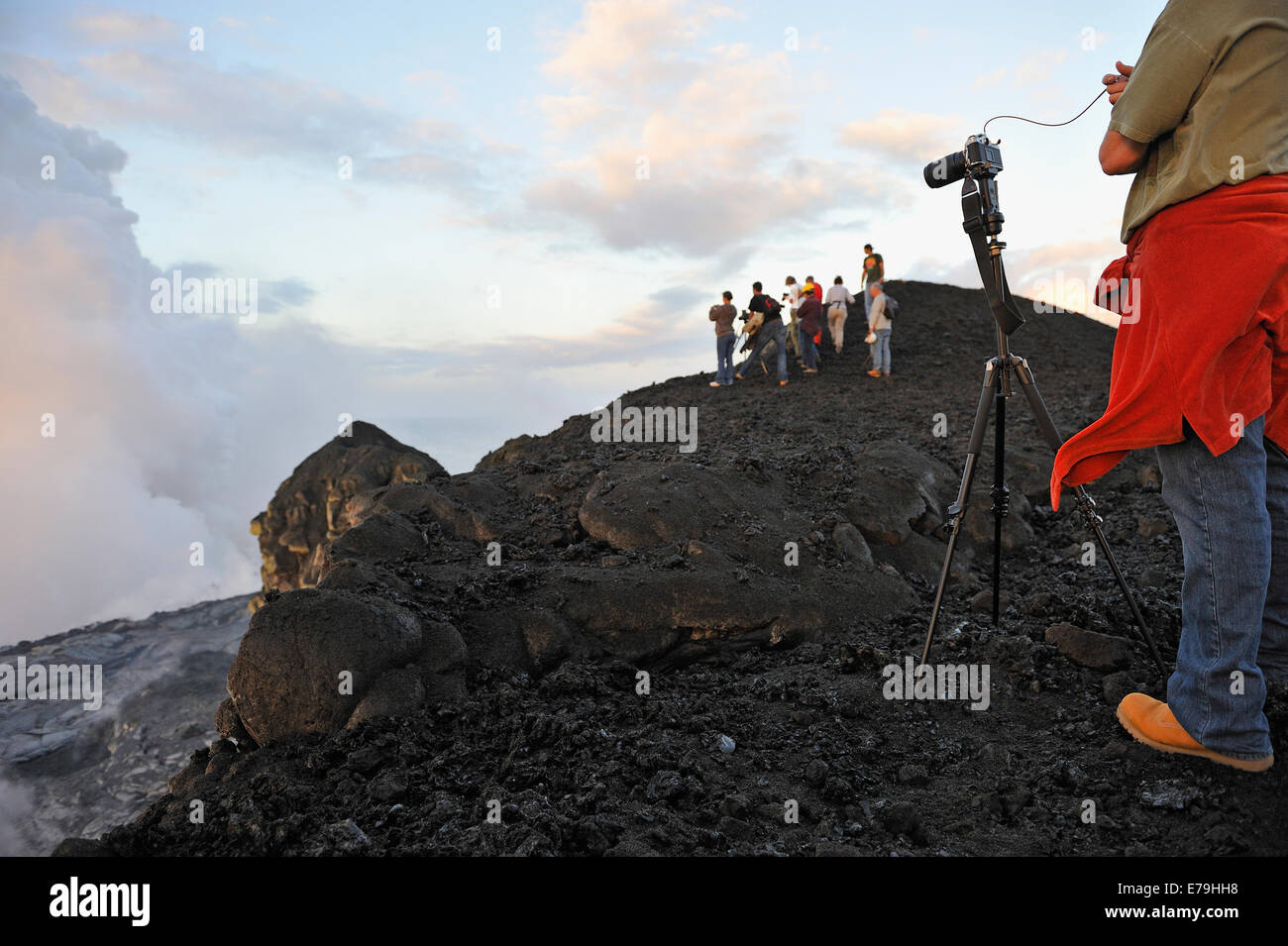 El hombre tomando fotos de la lava fluyendo hacia el océano y vapor, volcán Kilauea, Big Island, parque nacional de los volcanes de Hawaii. Foto de stock