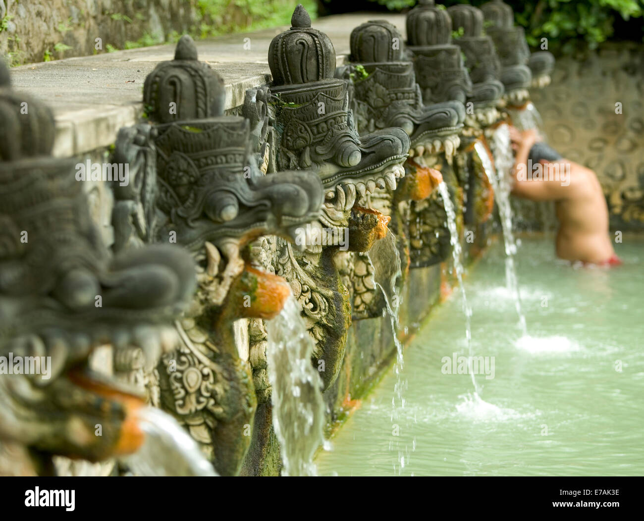 Persona bañarse en piedra tallada dragones en piscinas termales en Bali, Indonesia. Foto de stock