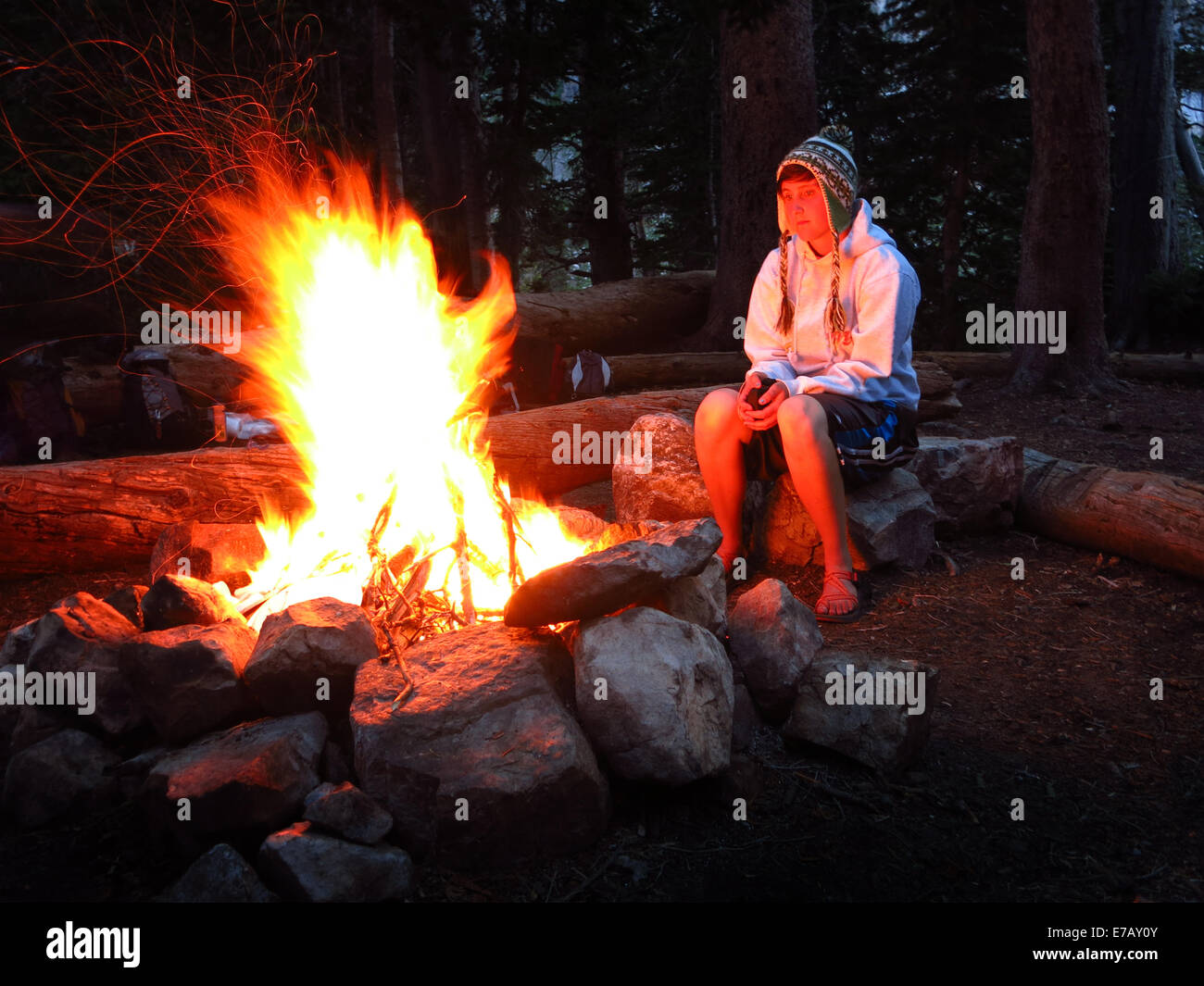 Mujer mirando su fogata mientras camping solos Foto de stock