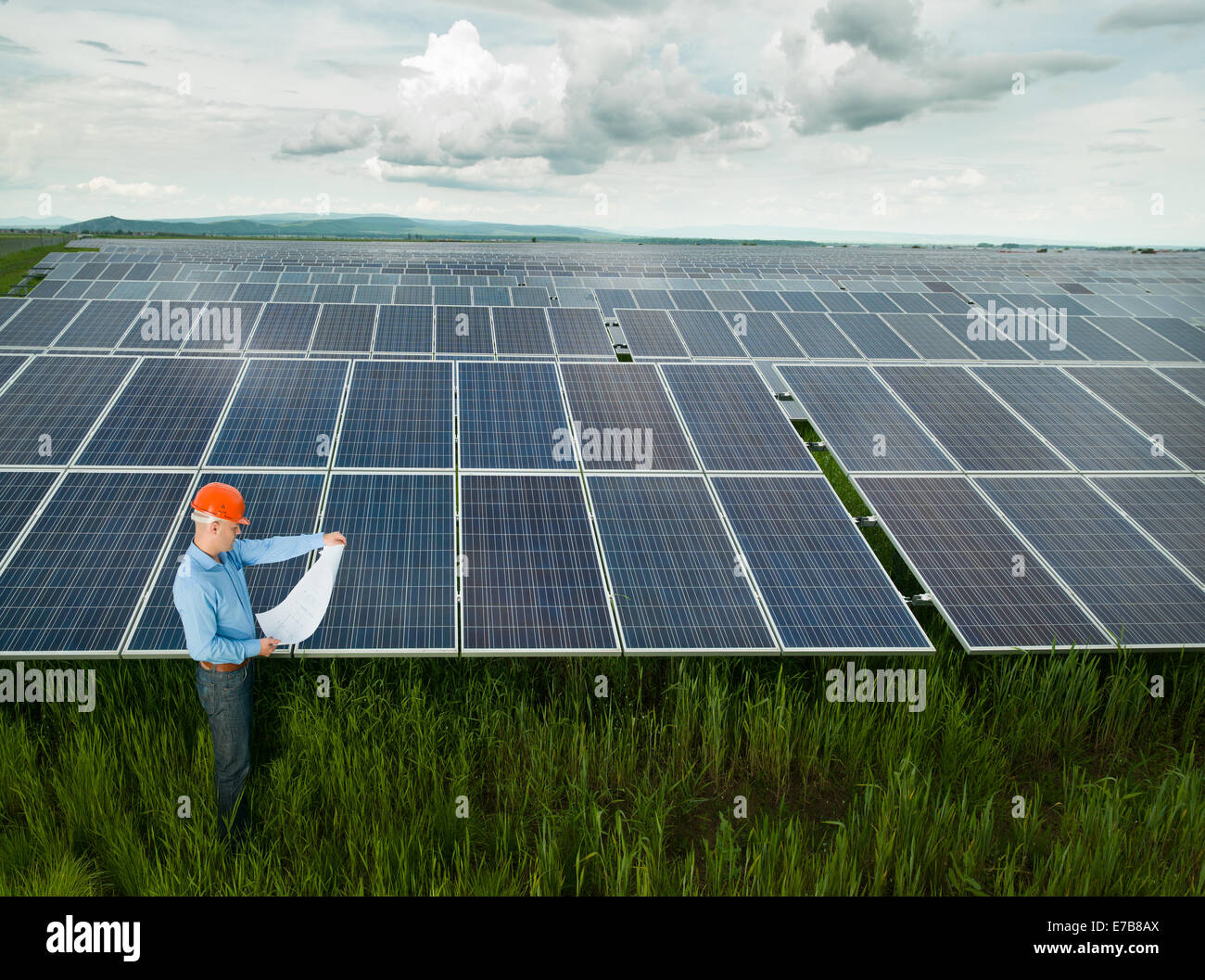 Electricista macho y lectura permanente anteproyectos en estación de energía solar Foto de stock