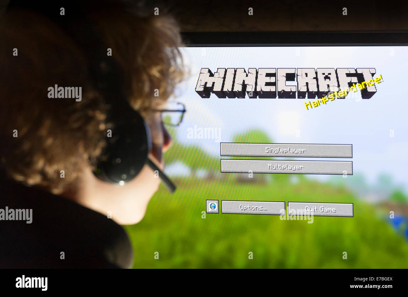 Un adolescente se sienta delante de la pantalla de su ordenador y juega el juego de ordenador Minecraft, desarrollado por la compañía sueca Mojang Foto de stock