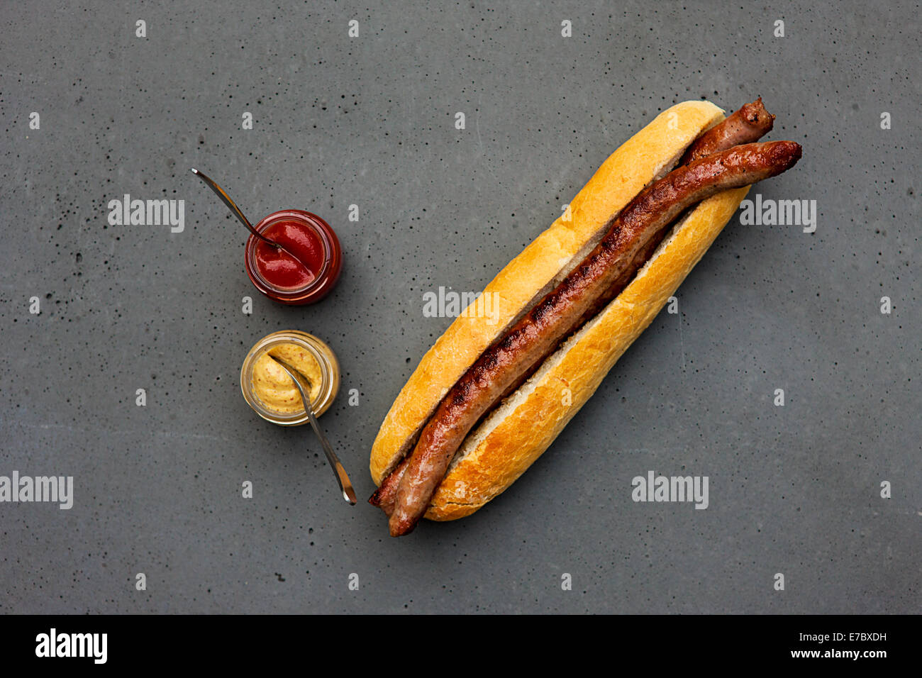 Clásico moderno hot dog con salchicha de cordero, bun, ketchup, mostaza en tabla de hormigón Foto de stock