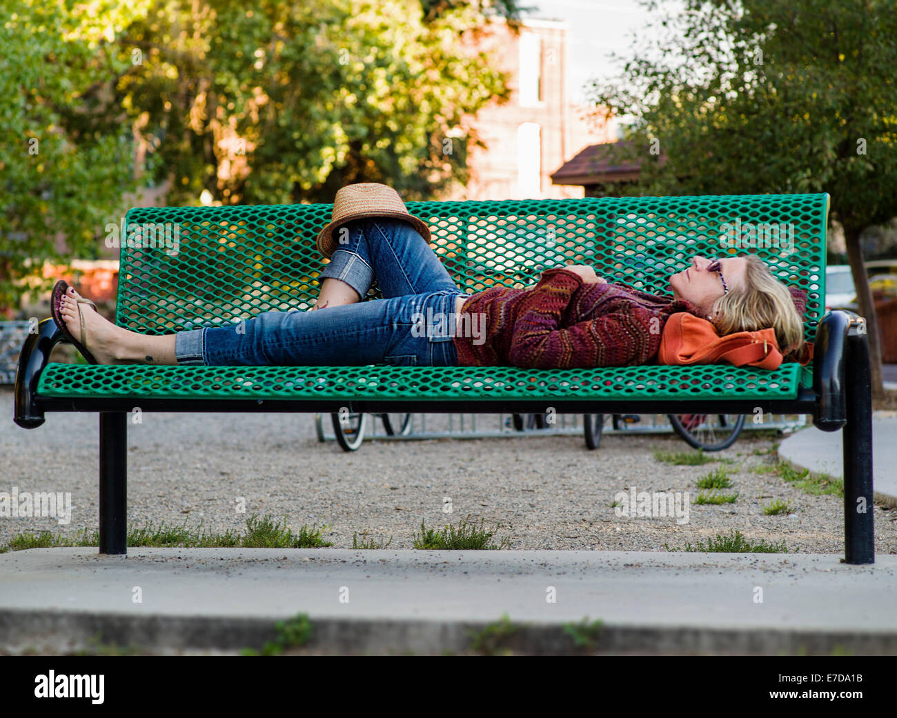 Mujer durmiendo en un banco del parque, el río Arkansas, Salida, Colorado, EE.UU. Foto de stock