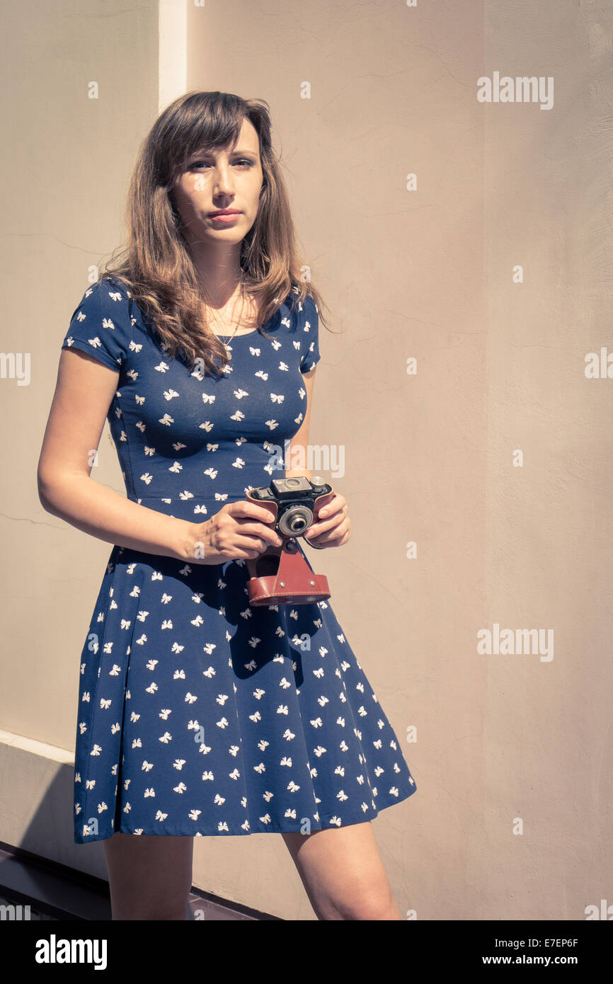 Young hipster chica caminando con cámara de película antigua Foto de stock