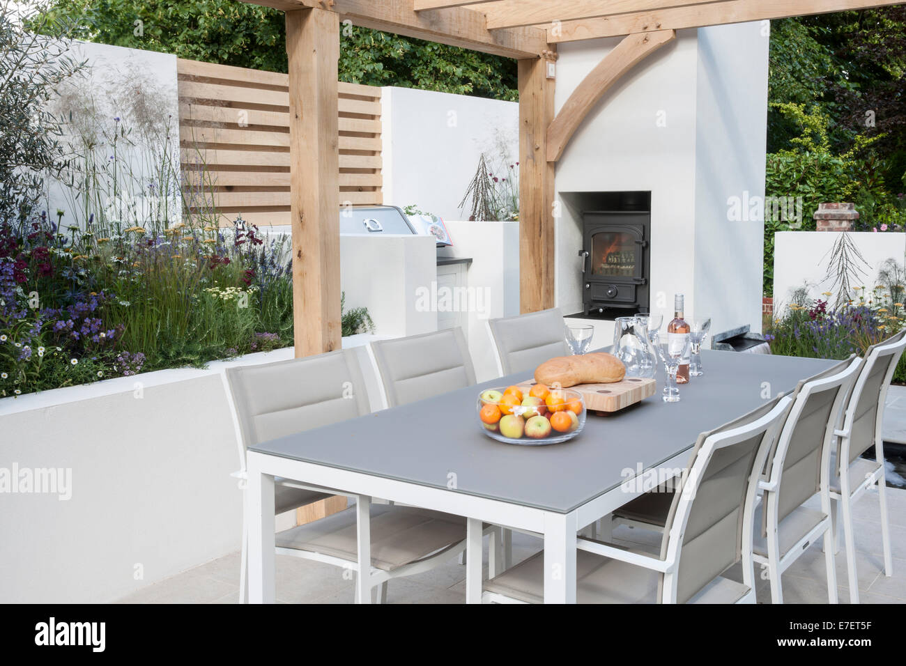 Jardín - vista del jardín contemporáneo al aire libre comedor mobiliario zona de estar patio con mesas y sillas cocina de leña al aire libre Reino Unido Foto de stock