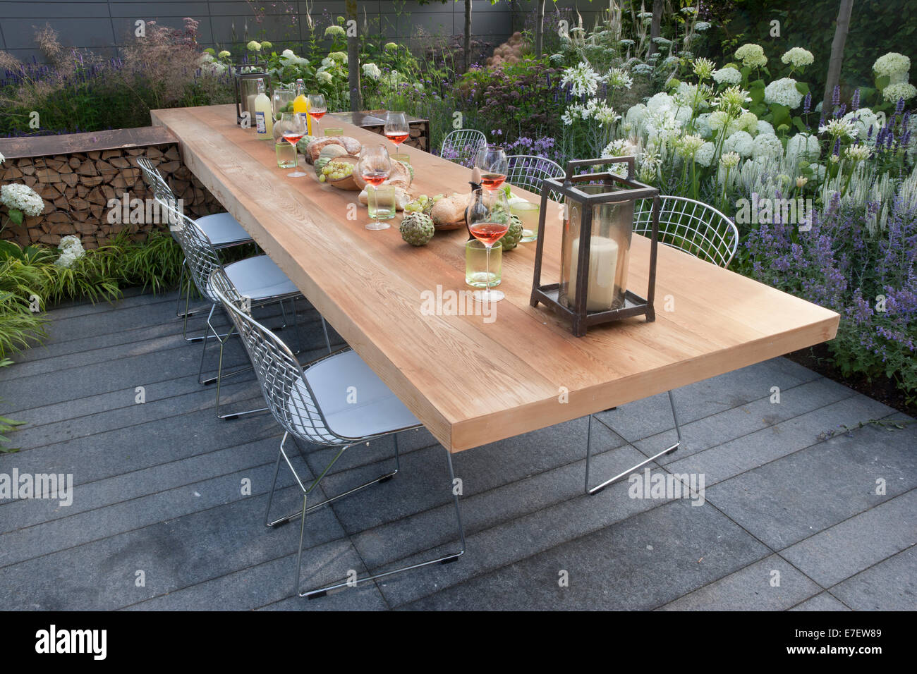 Pequeño jardín urbano con mesa de patio de piedra y sillas al aire libre comedor muebles plantar flores blanco Agapanthus Hydrangea arborescens flores Reino Unido Foto de stock