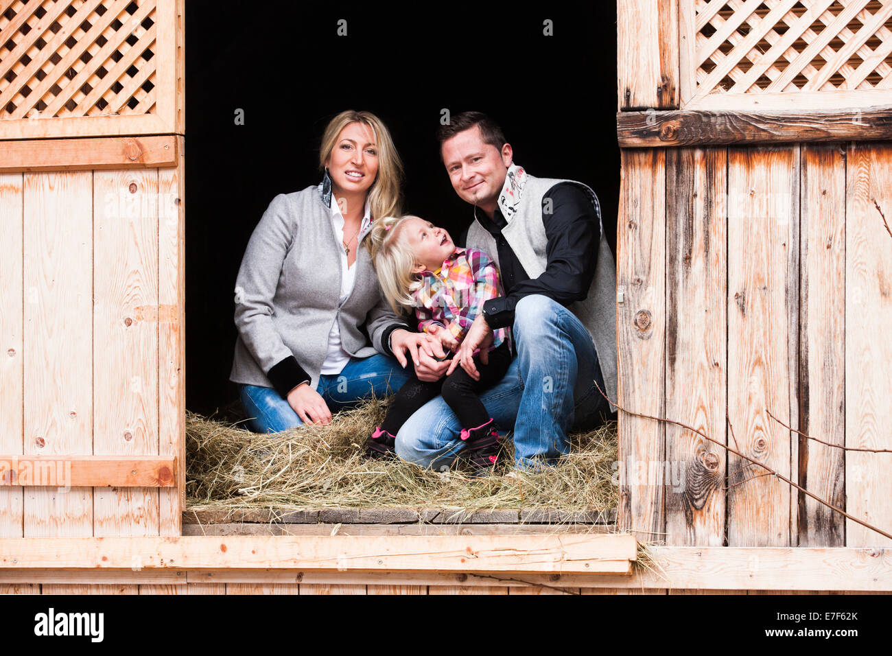 Familia joven sentado en el granero de heno, en el norte del Tirol, Austria Foto de stock