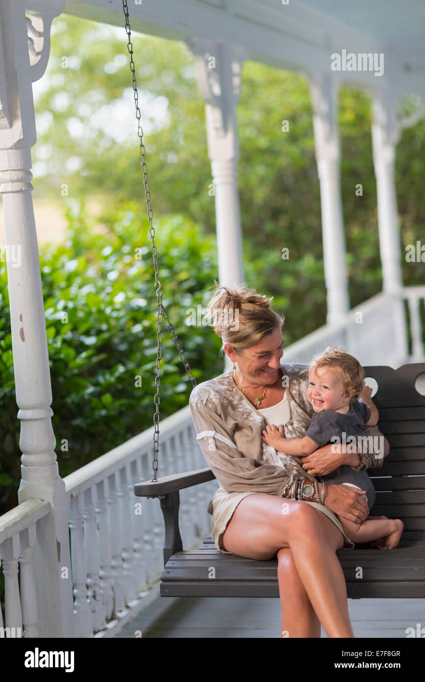Caucasian madre y niño sentado en el columpio en el porche Foto de stock