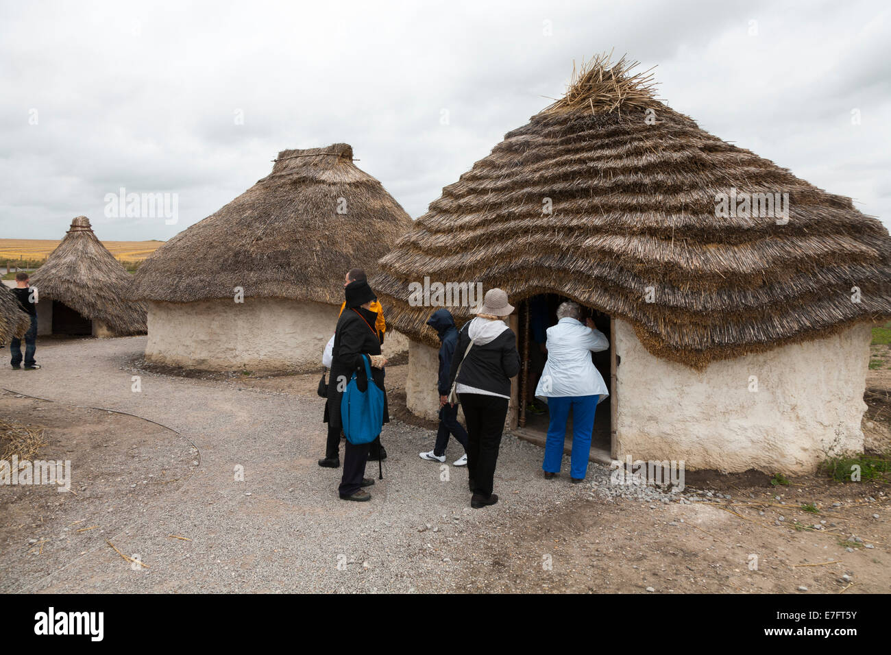 Los turistas ver recreado en la edad de piedra neolítica cabaña / stoneage chozas con techo de paja y techos / Exposición el centro de visitantes de Stonehenge Stone Henge UK Foto de stock