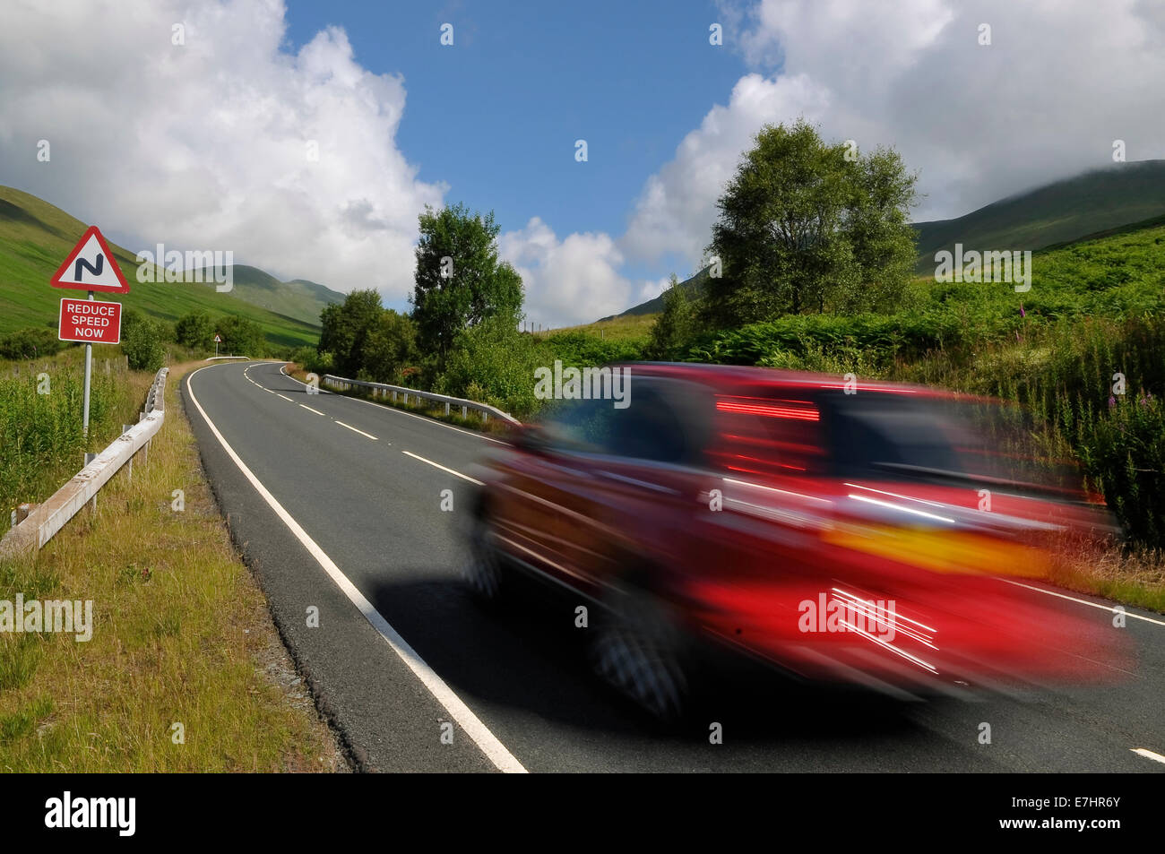 Coche rojo en la carretera de montaña en Higland, Escocia. Foto de stock