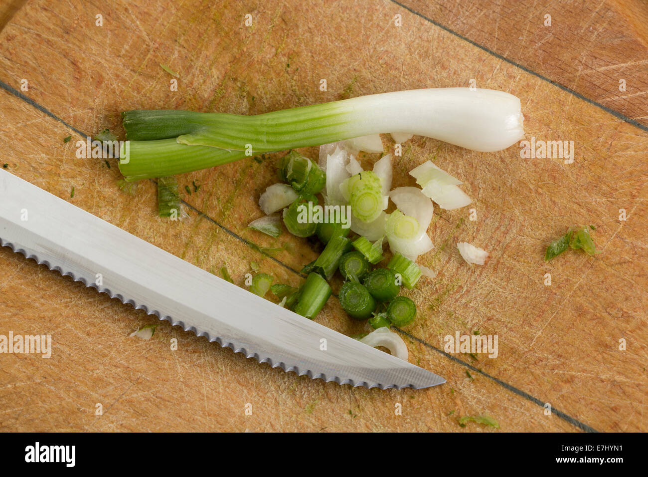 Cebolleta y un cuchillo sobre una tabla para cortar Foto de stock