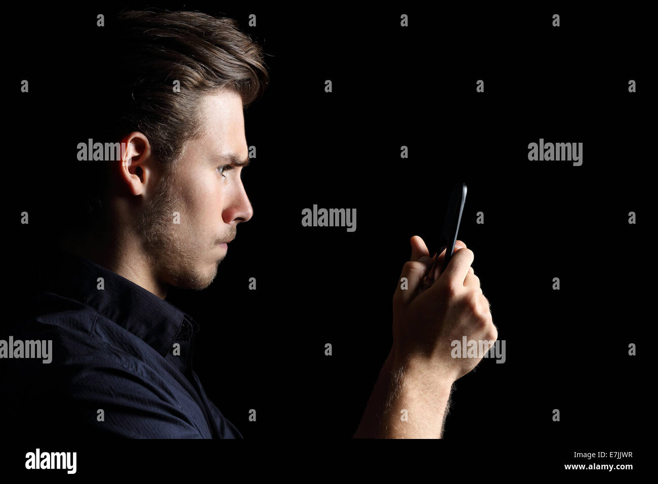 Obsesionado enojado adolescente texting en el teléfono inteligente aislado en un fondo negro Foto de stock