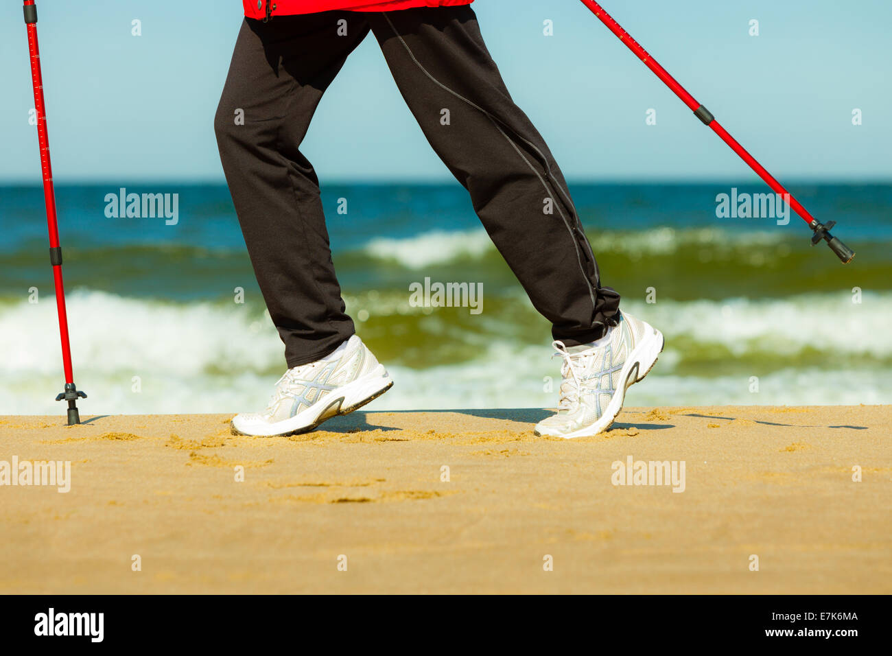Nordic Walking. Primer plano de piernas femeninas caminatas en la playa