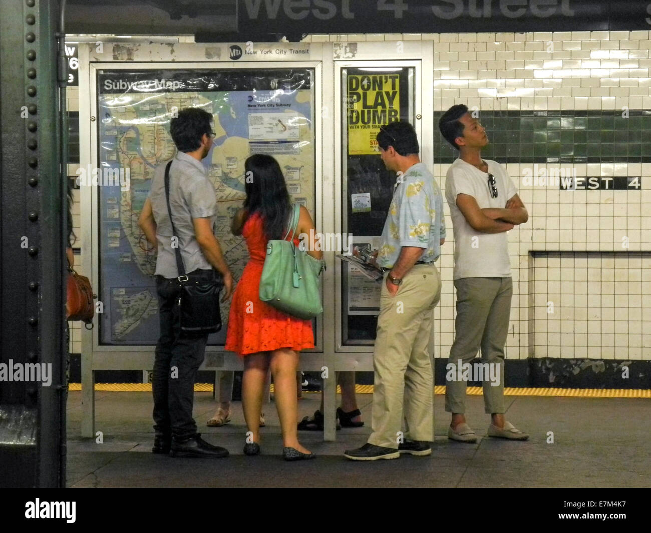 Los turistas americanos asiáticos en la Ciudad de Nueva York, leer un mapa de metro en West 4th Street, una estación de lower Manhattan. Nota firmar. Foto de stock