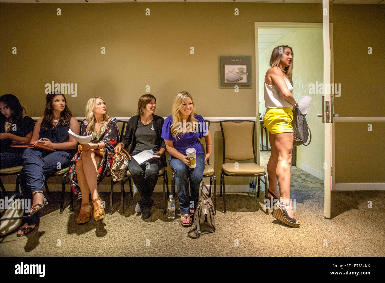 Un grupo de mujeres jóvenes y atractivas en Costa Mesa, California, esperar en un pasillo del hotel, mientras que uno de ellos va a su entrevista en vídeo a una audición para el programa de televisión 'Licenciado'. Foto de stock