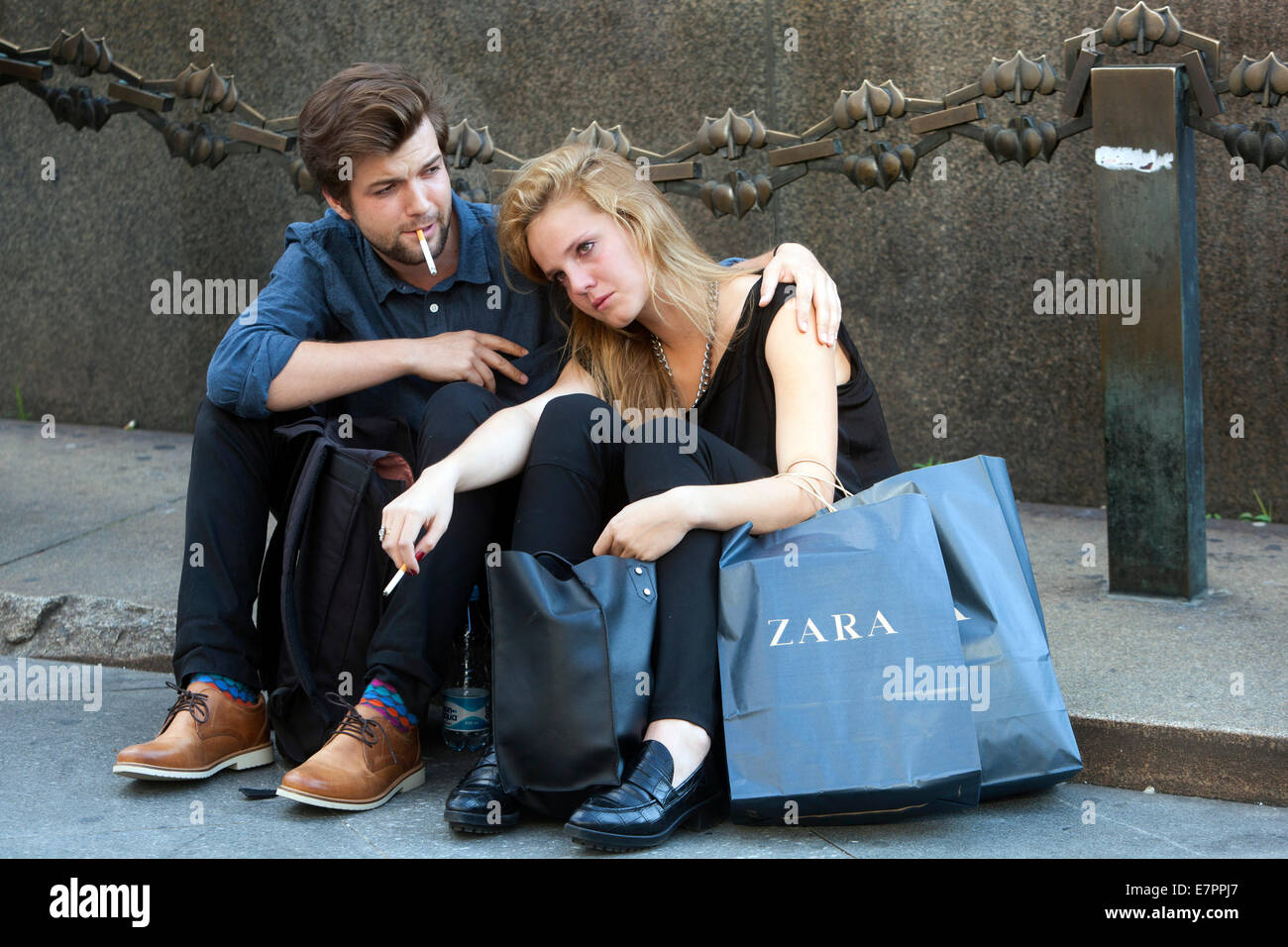 Compras en Praga, pareja joven cansada descansando después de ir de compras bajo el monumento de San Wenceslao, Praga República Checa gente Zara bolsa de compras Foto de stock
