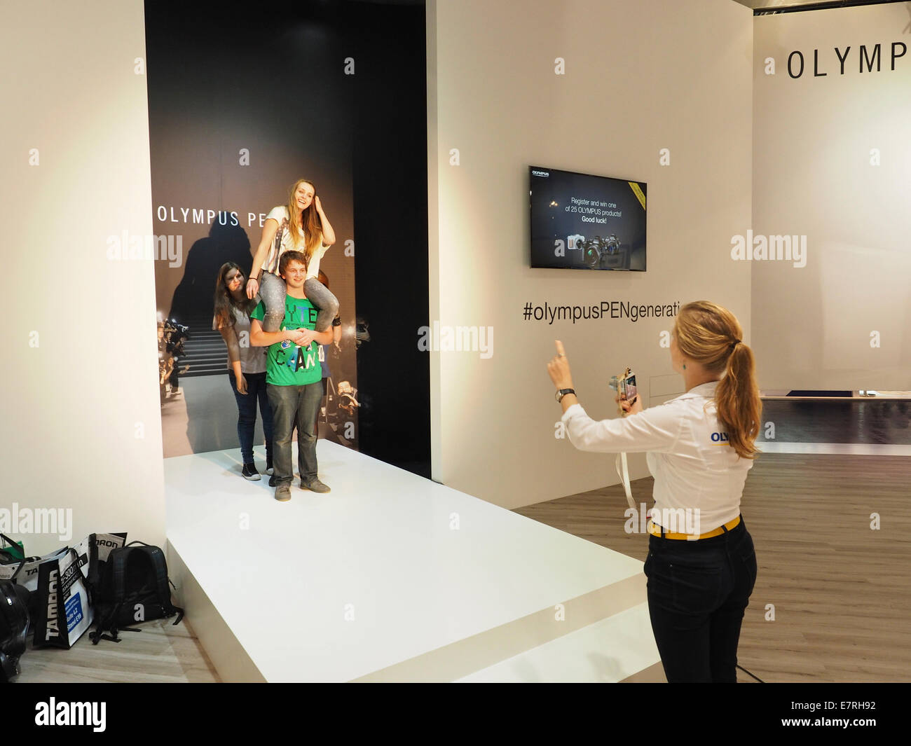 Photokina 2014 mujer fotógrafo tomando fotos de jóvenes visitantes con una cámara de sistema Olympus Pen mirrorless. Foto de stock