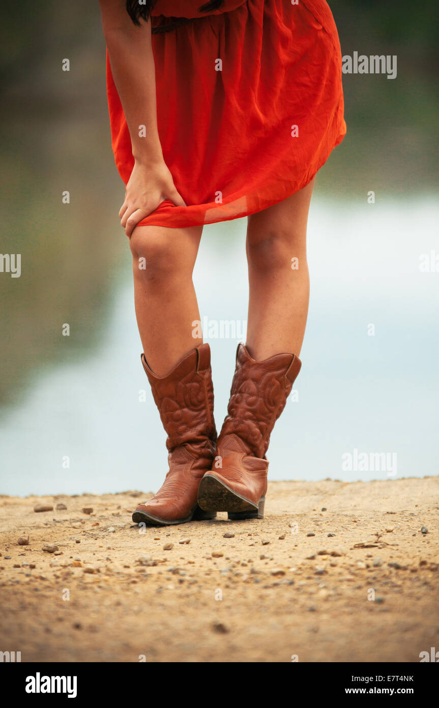 Una chica con un vestido rojo y botas de vaquero Fotografía de stock - Alamy