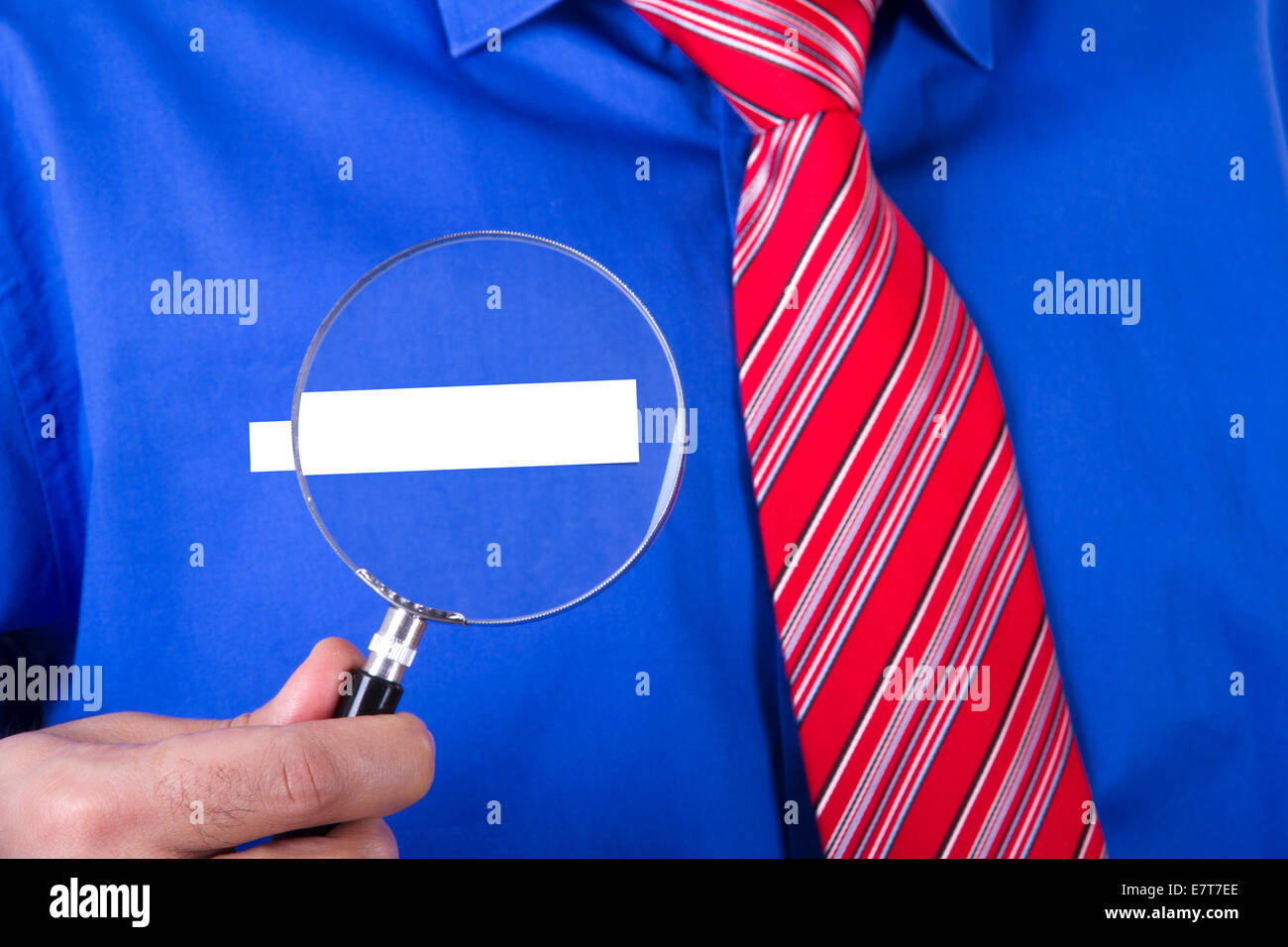 Empresario con corbata roja y camisa azul mostrando su título de etiqueta  en blanco con lupa Fotografía de stock - Alamy