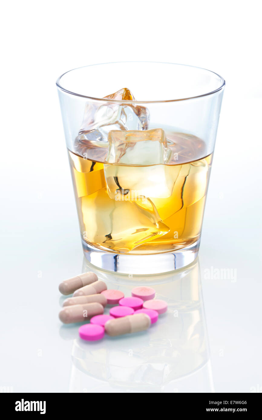 Un vaso de whisky y varios medicamentos de venta con receta médica. Foto de stock