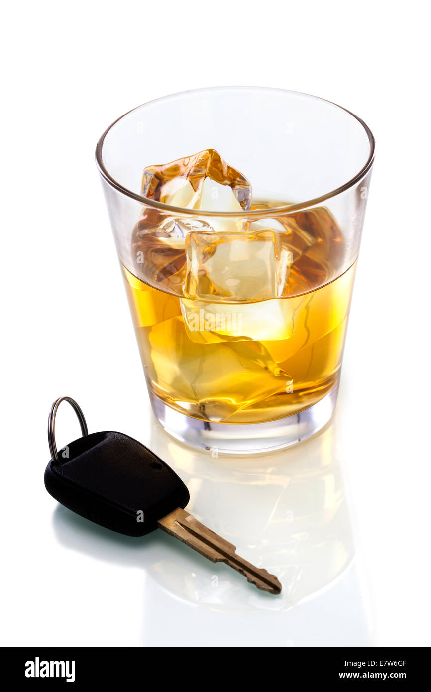 Un disparo de whisky y un conjunto de llaves del coche sobre un fondo blanco. Foto de stock