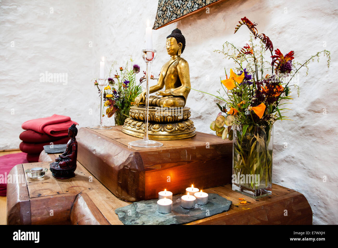santuario budista con el Buda meditando, velas, ofrendas florales Fotografía de stock - Alamy