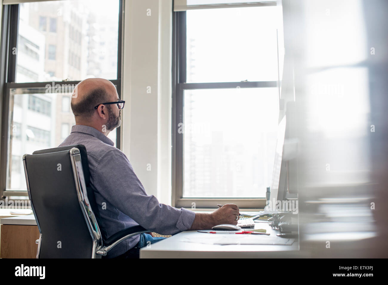 Vida de oficina. Un hombre sentado en un escritorio con una computadora,  mirando fijamente a la pantalla Fotografía de stock - Alamy